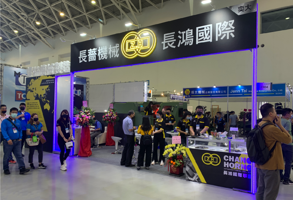 2023 高雄扣件展長鴻國際/長薔機械攤位,黑底黃字門楣與藍紫色燈條,買家在攤位前洽談