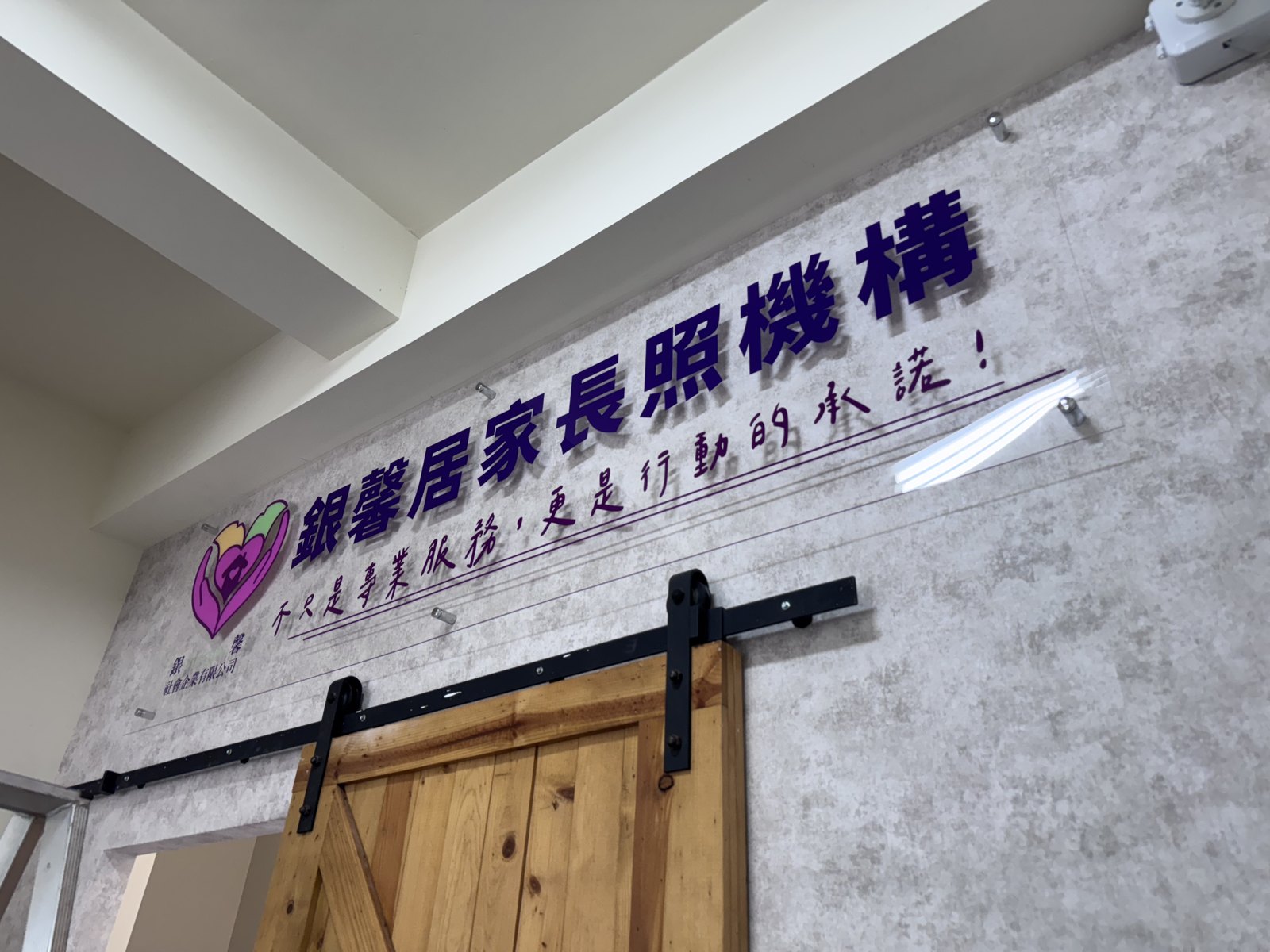形象牆斜角特寫,銀馨的品牌標語以手寫字體排在機構名稱下方