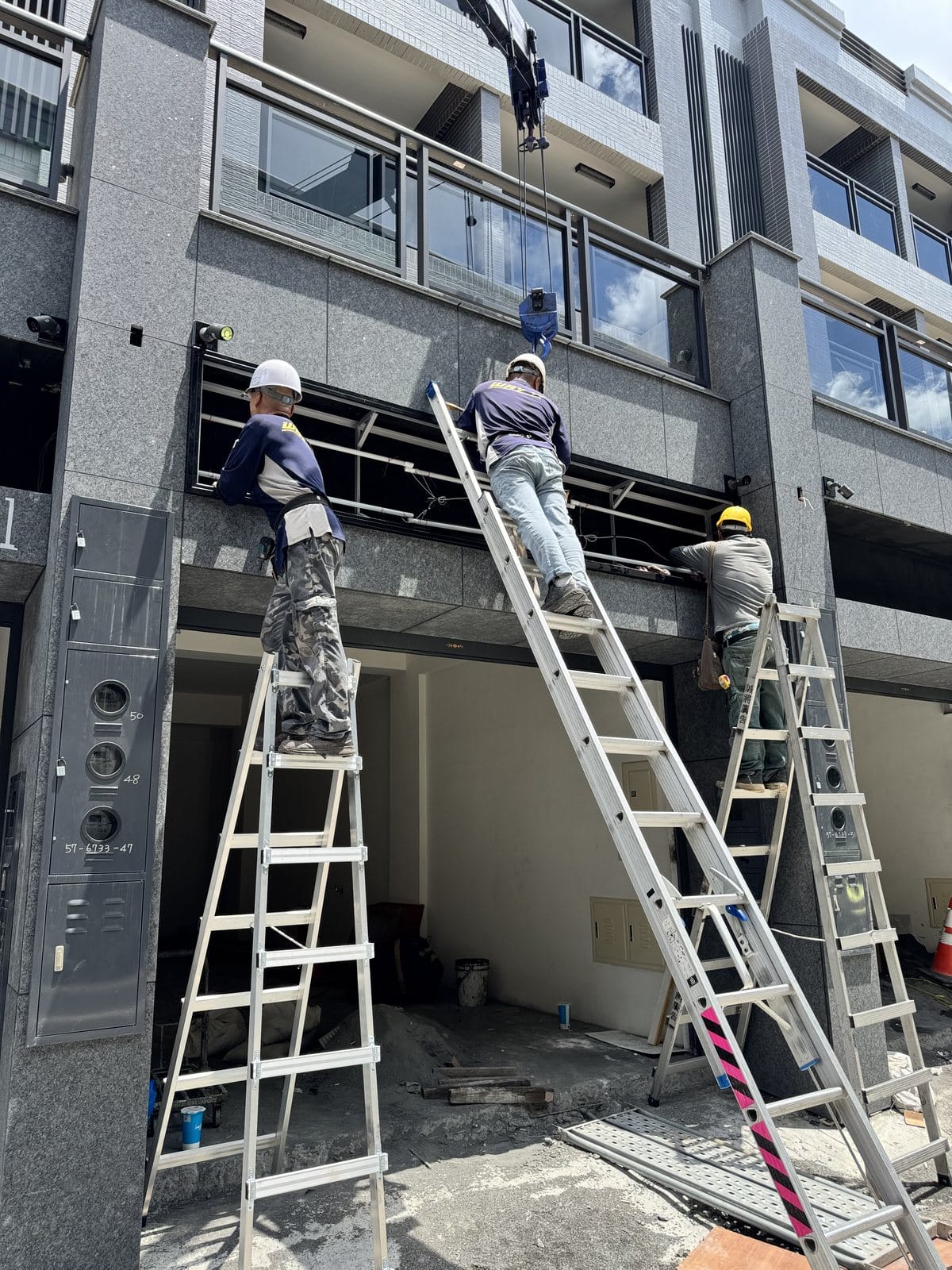 招牌安裝高處作業:兩名師傅雙梯施工,固定建案店面招牌結構,高雄招牌施工