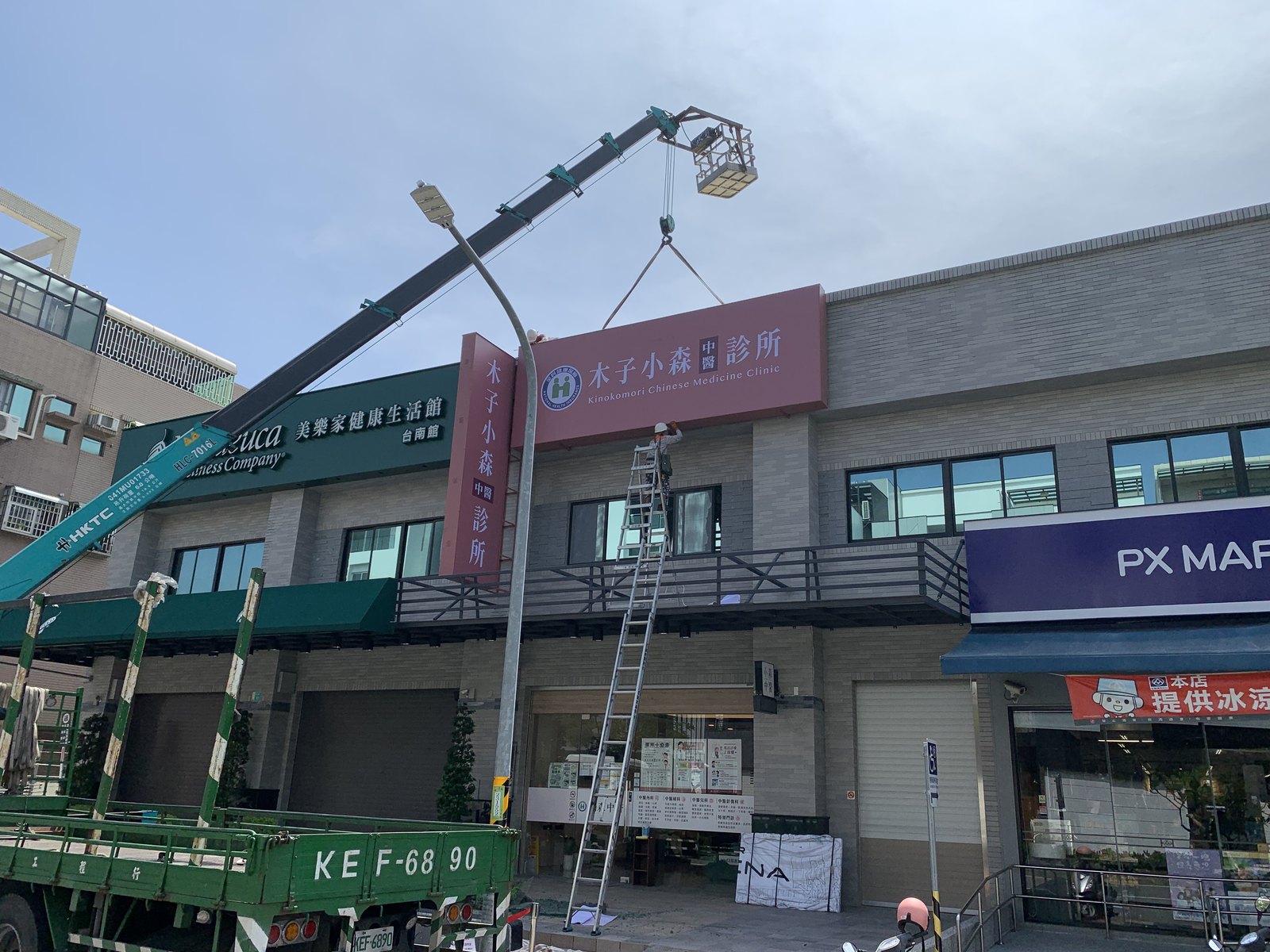 吊車吊掛無接縫招牌板面至二樓立面進行安裝