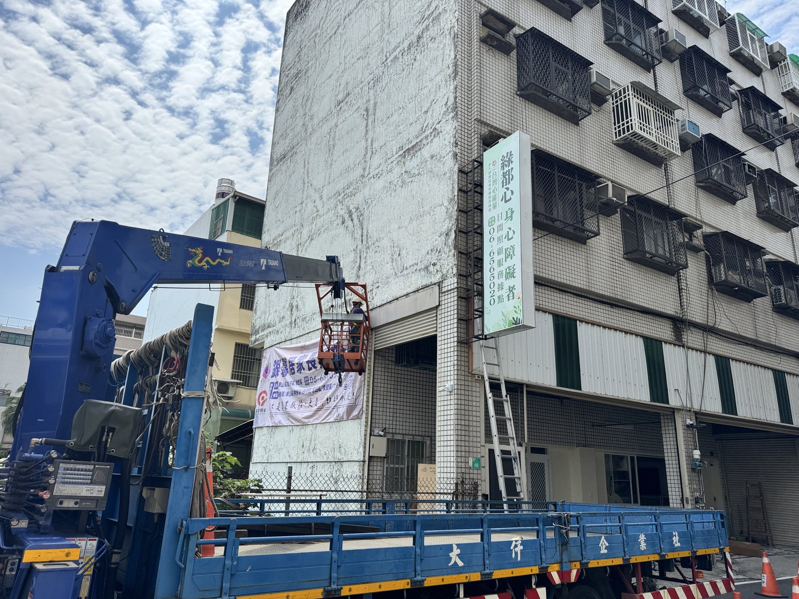高空作業車配合安裝銀馨居家長照機構的側牆帆布輸出