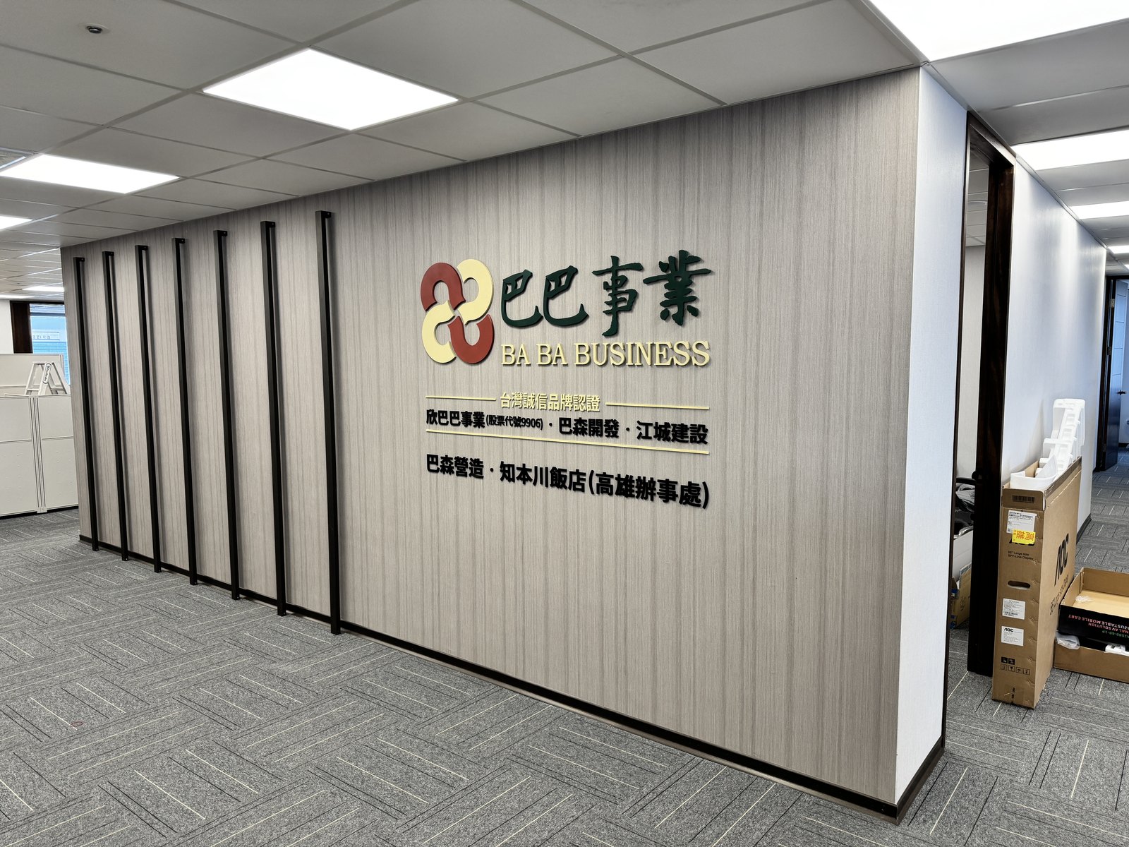從辦公室走道看整面公司形象牆,木紋牆板搭配黑色金屬方管