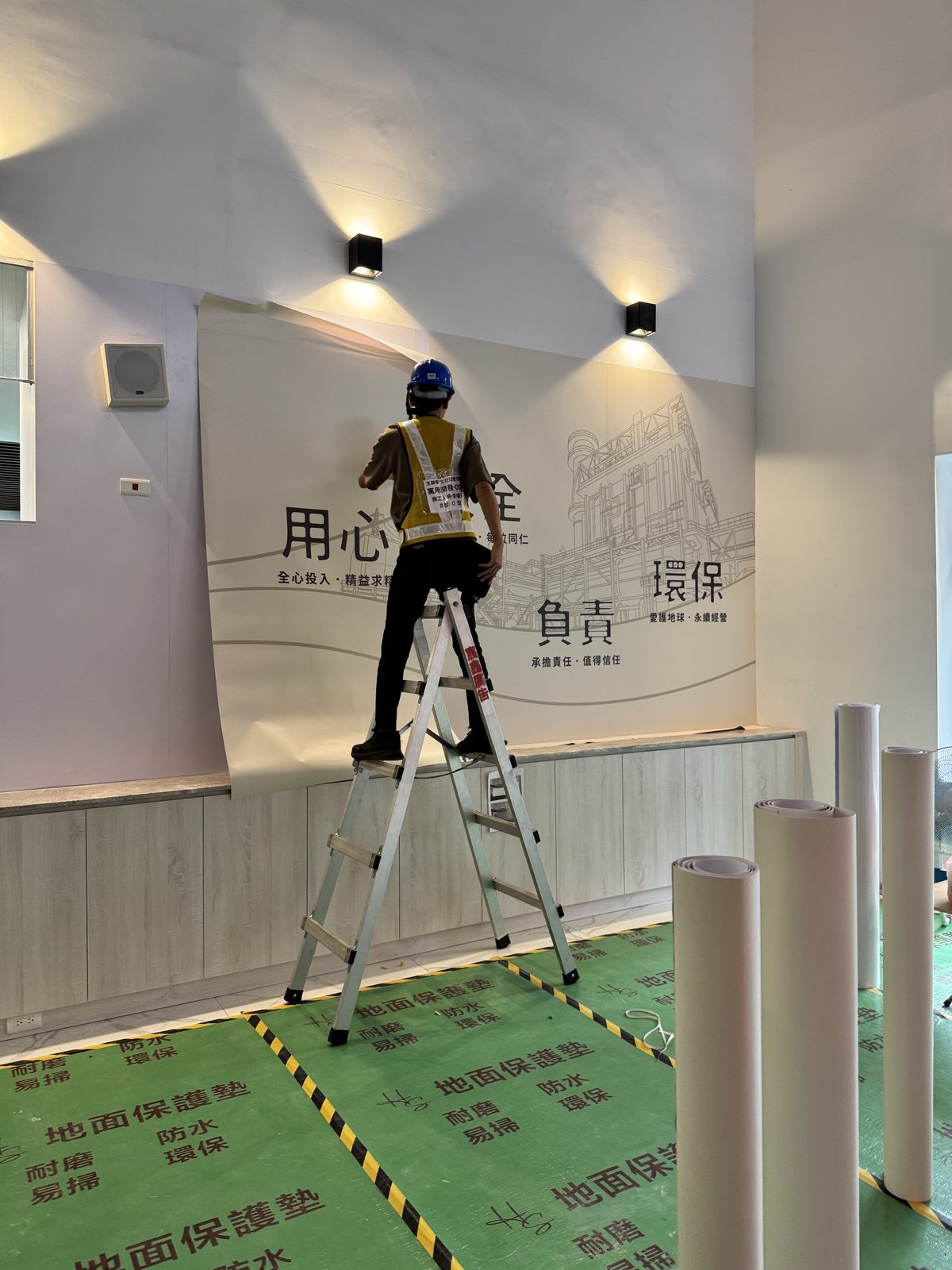 形象牆大圖輸出施工,工班於高處進行貼合作業